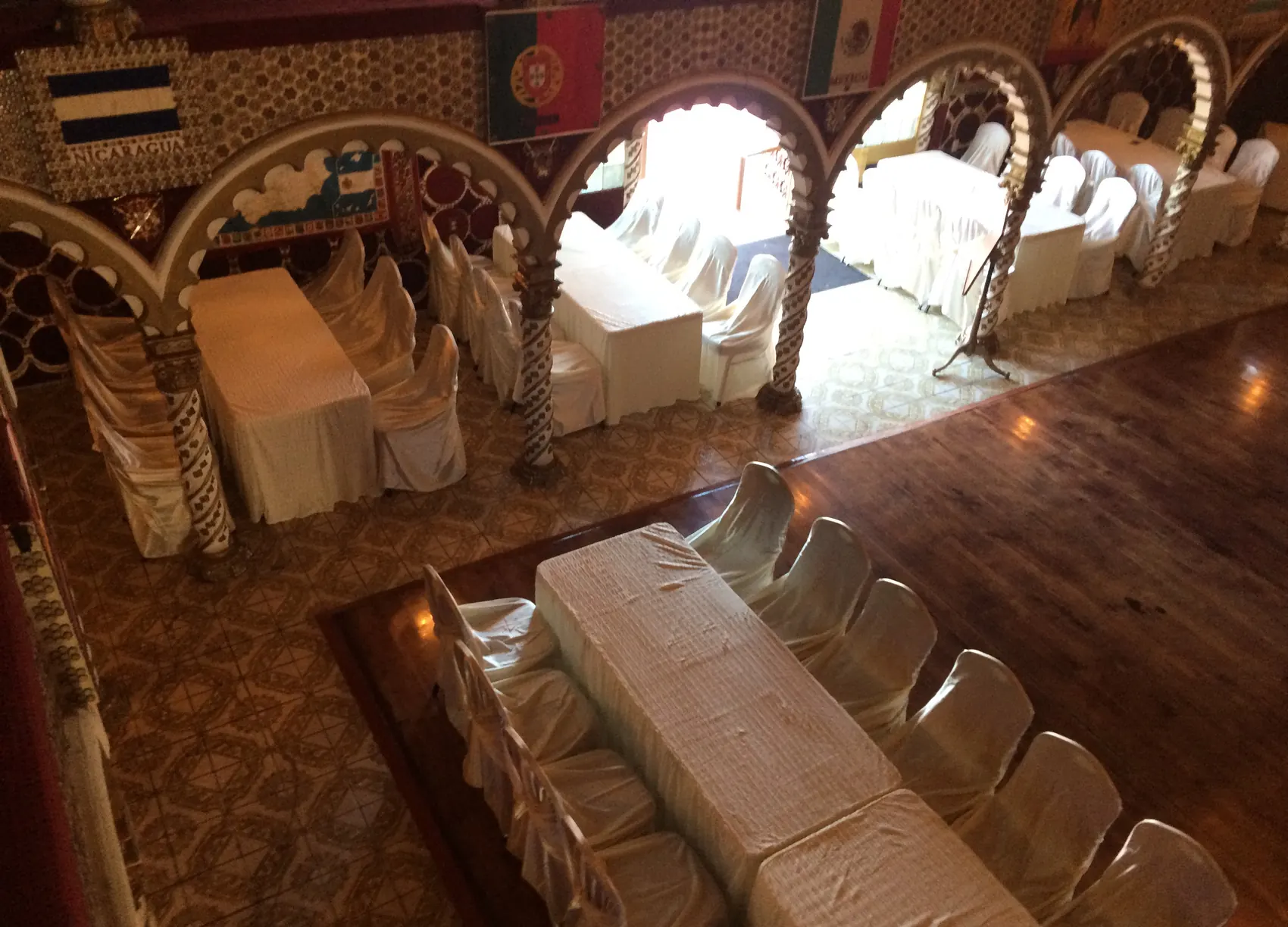 White-draped banquet tables running along the wood floor beneath the arches.