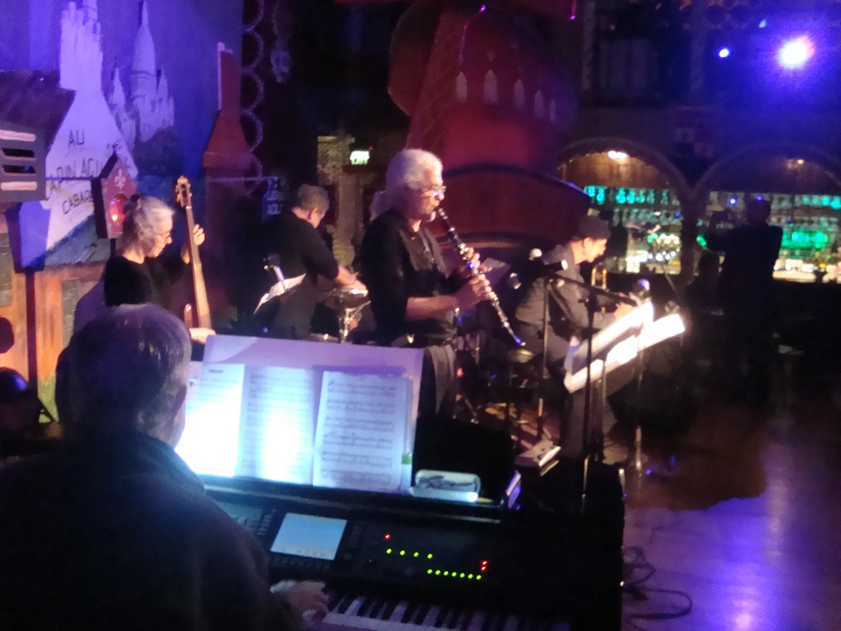 A bass player and horns performing on the blue-lit stage.