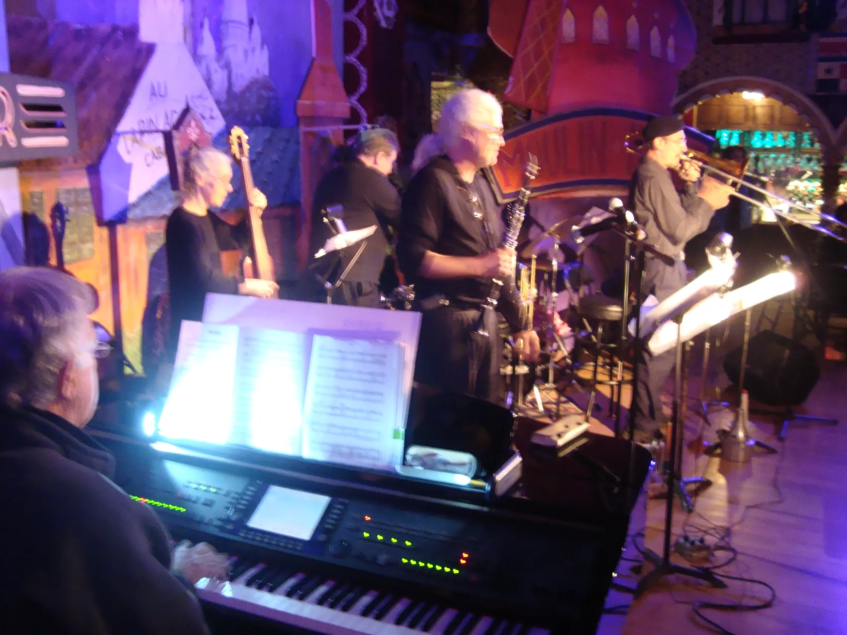 A band on stage in blue light, a keyboardist in the foreground.