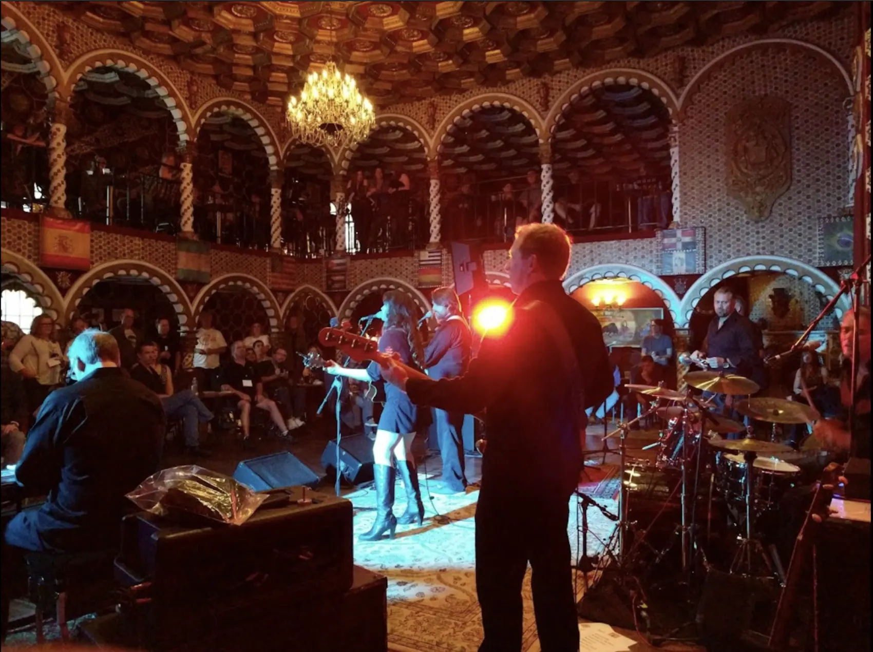 A band and singer on stage, lit from behind under the arches.