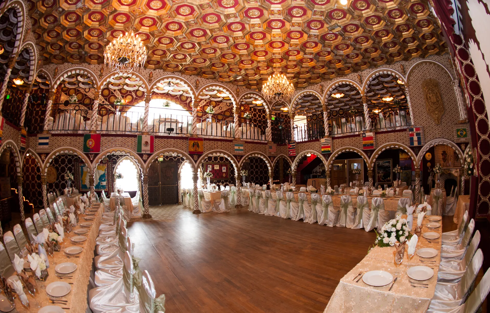 A wide banquet set across the ballroom, chandeliers and ornate ceiling above the long tables.