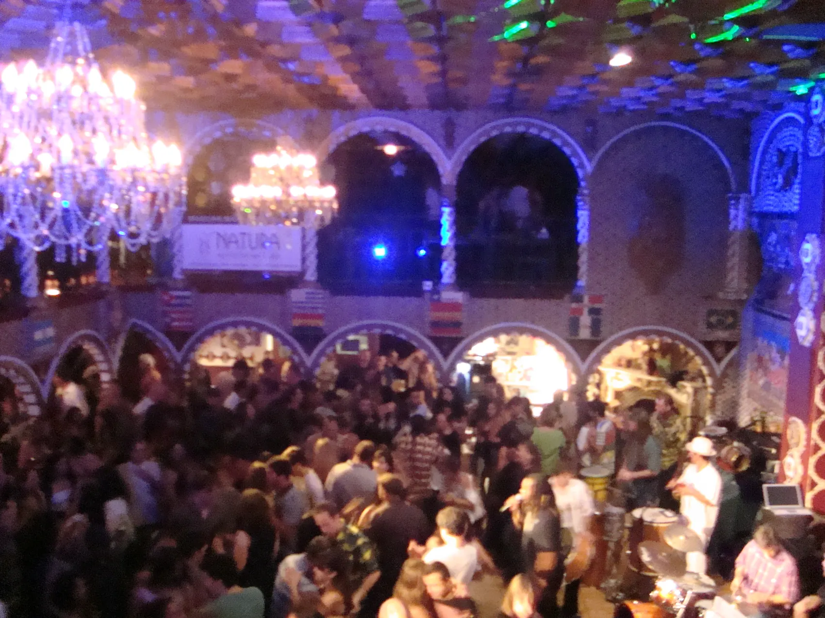 A crowded night on the floor, chandeliers and glowing arches over the dancers.