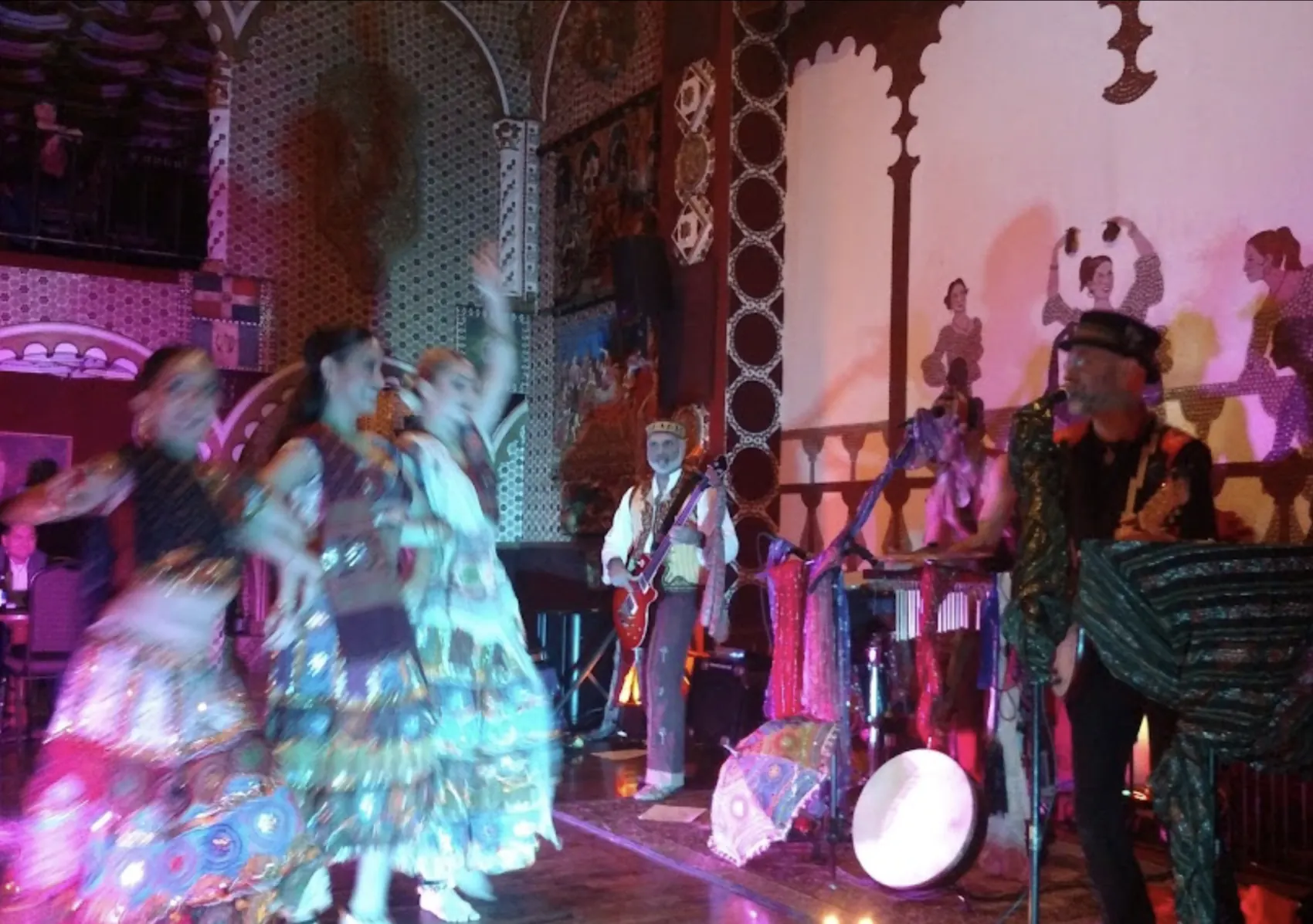 Flamenco dancers performing on stage in bright ruffled costume.