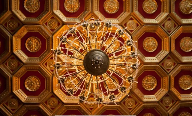 The gilded octagonal ceiling medallion of the ballroom in red and gold.