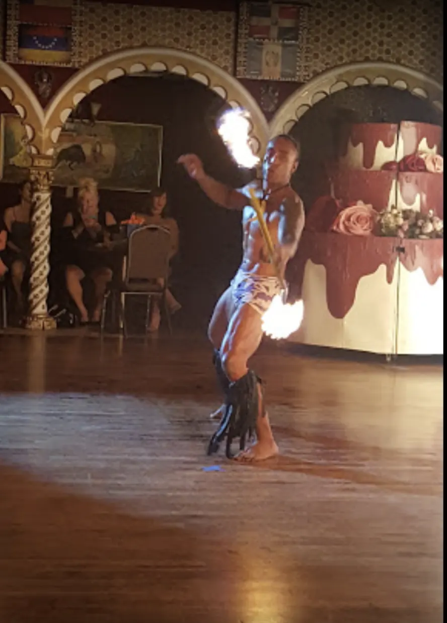 A Latin dancer in a red dress mid-step on the wood floor.