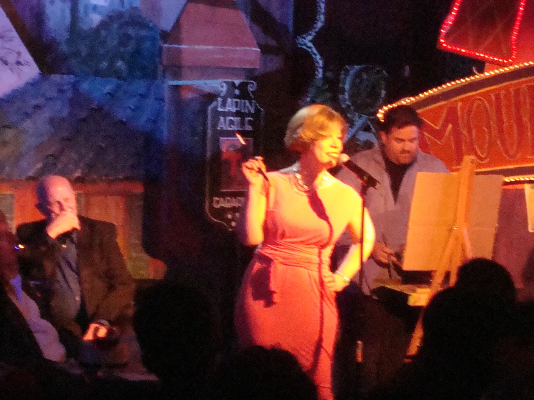 A performer in a red dress on stage under warm light.