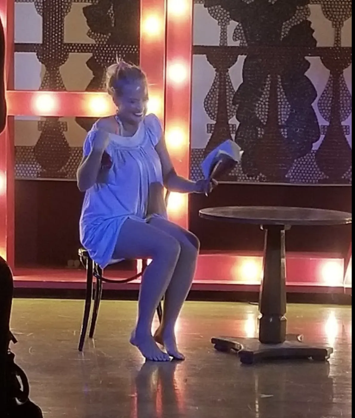 A singer performing on a stool under blue stage light.
