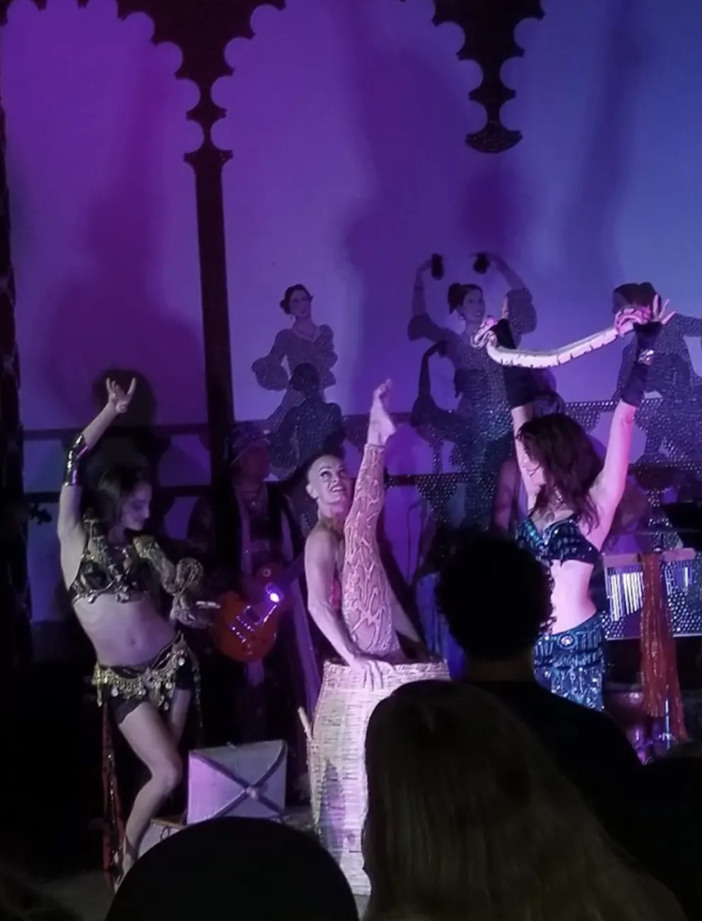 Couples social dancing under purple stage light.
