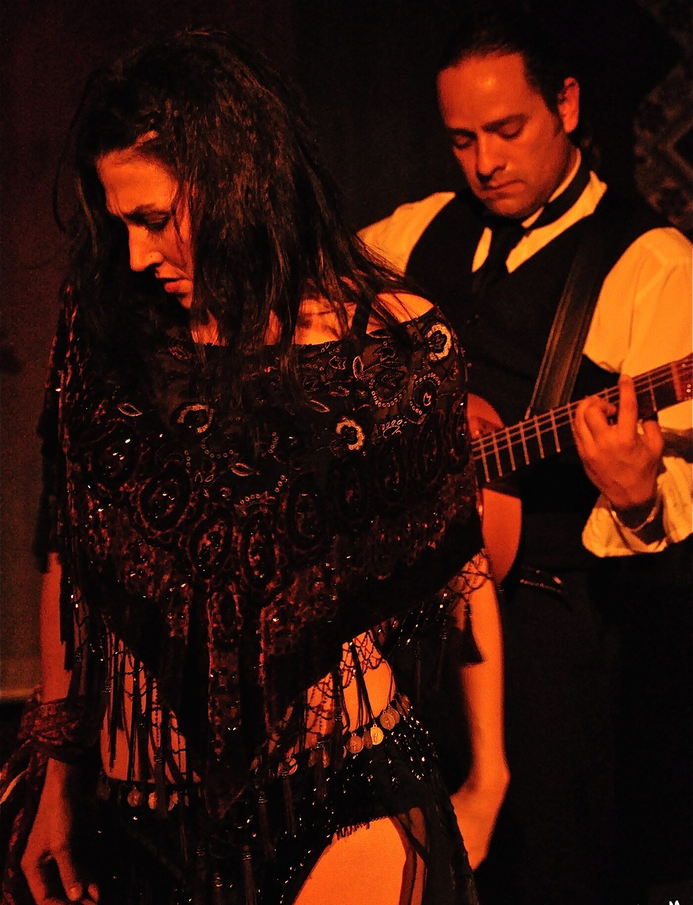 A dancing couple posed close together under stage light.